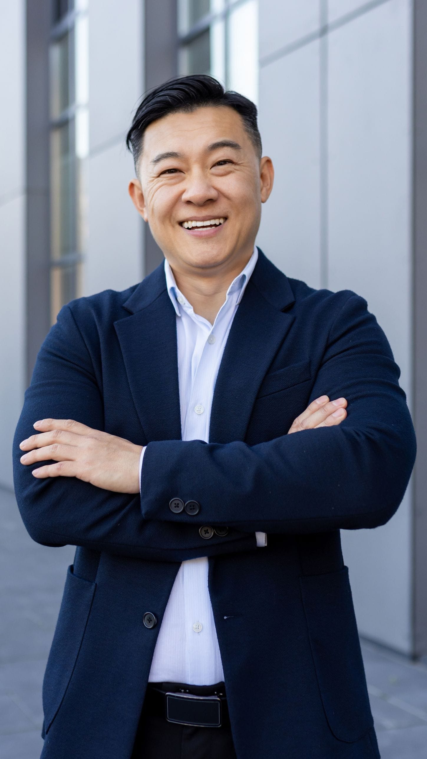 スーツ姿で腕を組み、微笑んでいる男性。ビジネスパーソンとしての自信とプロフェッショナリズムが表れています。